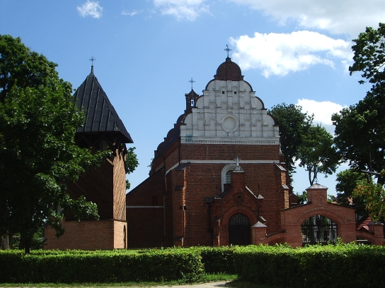 Kolorowe współczesne zdjęcie. Przedstawia fasadę XVI-wiecznego kościoła w Broku. Obok kościóla dzwonnica.