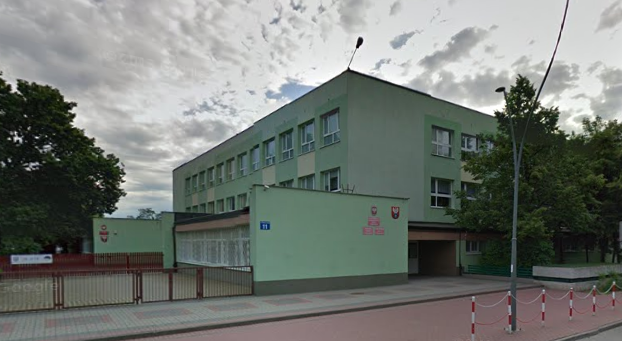 Współczesne zdjęcie. Przedstawia widok na budynek z wejściem, przed nim ogrodzenie. Jest to Zespół Szkół Ogólnokształcących Nr2 im. Króla Jana III Sobieskiego w Legionowie.