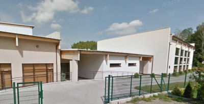 Współczesne zdjęcie. Przedstawia widok na rząd niskich budynków, przed którymi znajduje się ogrodzenie. Jest to Gimnazjum nr 15 im. Jana III Sobieskiego w Bielsku-Białej. 