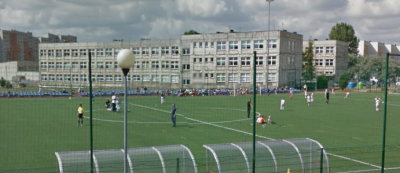 Współczesne zdjęcie. Przedstawia widok na boisko sportowe i budynek szkoły w tle. Jest to Gimnazjum nr 1 im. Jana III Sobieskiego w Częstochowie. 