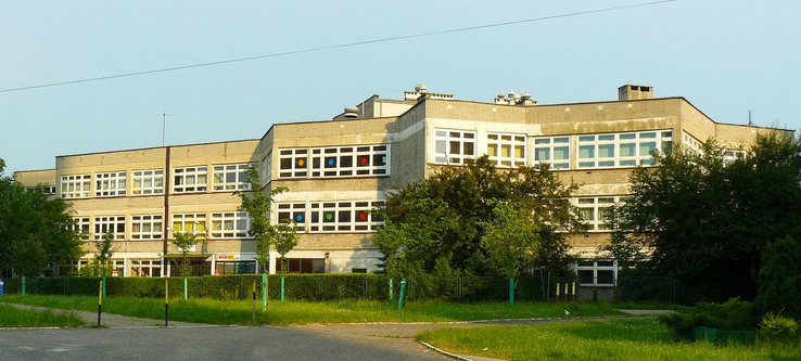 Współczesne zdjęcie. Przedstawia widok na budynek przed którym znajduje się ogrodzenie. Jest to Szkoła Podstawowa nr 2 im. Jana III Sobieskiego w Katowicach. 