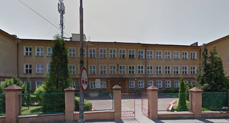 Współczesne zdjęcie. Przedstawia widok na budynek, przed którym stoi ogrodzenie. Jest to Szkoła Podstawowa nr 12 im Jana III Sobieskiego w Sosnowcu. 