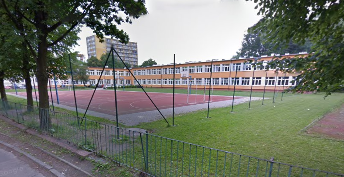 Współczesne zdjęcie. Przedstawia widok na boisko i budynek - szkołę. Jest to Gimnazjum nr 11 im. Jana III Sobieskiego w Tychach. 