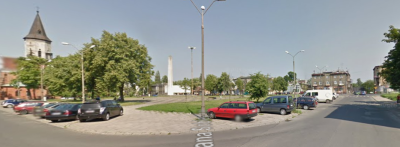 Współczesne zdjęcie. Przedstawia widok ulicę w mieście. Widzimy zabudowania i kościół po lewej stronie. Po prawej stronie kamienice. Jest to Ulica Jana Sobieskiego w Pabianicach. 