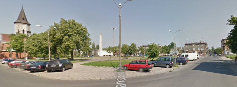 Współczesne zdjęcie. Przedstawia widok ulicę w mieście. Widzimy zabudowania i kościół po lewej stronie. Po prawej stronie kamienice. Jest to Ulica Jana Sobieskiego w Pabianicach. 