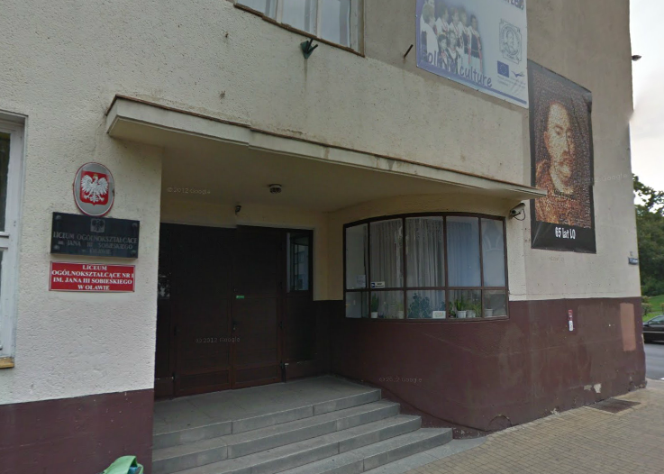 Współczesne zdjęcie. Przedstawia widok na budynek i wejście. Po prawej stronie plakat Jana III Sobieskiego. Jest to Liceum Ogólnokształcące nr I im. Jana III Sobieskiego w Oławie. 