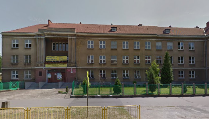 Współczesne zdjęcie. Przedstawia widok na budynek z wejściem, przed nim ogrodzenie. Jest to Zespół Szkól nr 12 im. Jana III Sobieskiego w Gorzowie Wielkopolskim. 