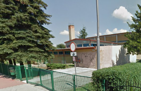 Współczesne zdjęcie. Przedstawia widok na niski budynek, zielone ogrodzenie i wejście. Jest to Publiczne Gimnazjum Nr 2 im. Jana III Sobieskiego w Lubaczowie. 