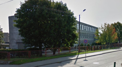 Współczesne zdjęcie. Przedstawia widok na budynek, przesłonięty drzewami. Z przodu droga. Jest to Zespół Szkół im. Jana III Sobieskiego w Żelistrzewie.