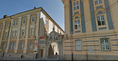 Współczesne zdjęcie. Przedstawia widok na fasady zabytkowych kamienic i wejście pomiędzy nimi prowadzące na dziedziniec. Jest to I Liceum Ogólnokształcące im. Jana III Sobieskiego w Nysie. 