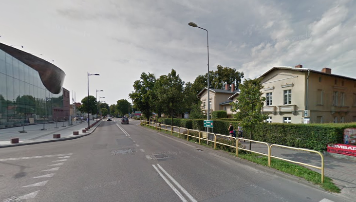 Współczesne zdjęcie. Przedstawia widok na miejską ulicę wraz z zabudowaniami. Jest to Ulica Jana III Sobieskiego w Wejherowie. 
