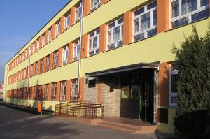 Współczesne zdjęcie. Przedstawia widok na wejście do budynku szkolnego. Jest to Publiczna Szkoła Podstawowa nr 1 im. Jana III Sobieskiego z Oddziałami Integracyjnymi w Szydłowcu. 