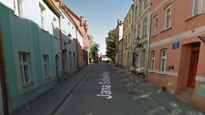 Współczesne zdjęcie. Przedstawia widok na ulicę wraz z zabudowaniami miejskimi. Sa to kolorowe kamienice, umiejscowione po obu stronach. Jest to Ulica Jana Sobieskiego w Gniewie. 
