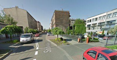 Współczesne zdjęcie. Przedstawia widok ruchliwej ulicy w mieście. Po prawej i lewej stronie pojedyncze budynki. Jest to Ulica Sobieskiego w Katowicach. 