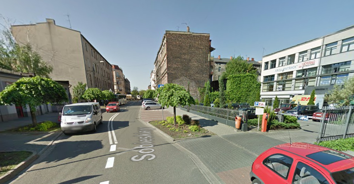 Współczesne zdjęcie. Przedstawia widok ruchliwej ulicy w mieście. Po prawej i lewej stronie pojedyncze budynki. Jest to Ulica Sobieskiego w Katowicach. 