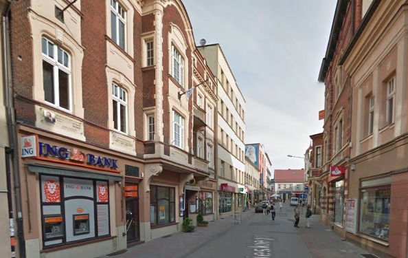 Współczesne zdjęcie. Przedstawia widok ulicy w mieście. Z prawej i lewej strony kamienice. Jest to Ulica Sobieskiego w Rybniku. 