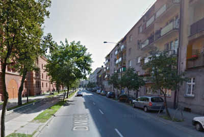 Współczesne zdjęcie. Przedstawia widok na ulicę z drzewami. Po prawej stronie współczesne bloki, po lewej stronie ceglane budynki. Jest to ulica Jana III Sobieskiego w Gnieźnie.