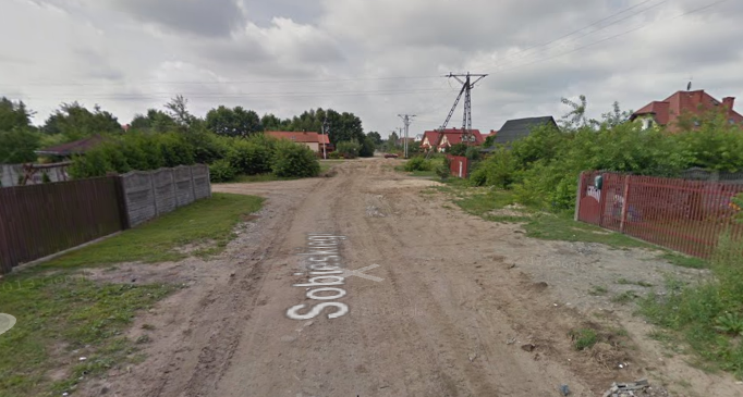 Współczesne zdjęcie. Przedstawia widok drogi wewnątrz osiedla domków jednorodzinnych. Jest to Ulica Sobieskiego w Markach. 