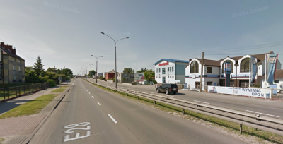 Współczesne zdjęcie. Przedstawia widok na ruchliwą ulicę wraz ze współczesnymi zabudowaniami po prawej i lewej stronie. Jest to Ulica Jana III Sobieskiego w Rumii. 