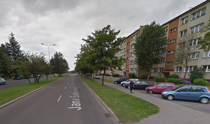 Współczesne zdjęcie. Przedstawia widok ulicę w mieście. Z prawej strony bloki i parking samochodowy. Jest to Ulica Jana Sobieskiego w Słupsku. 