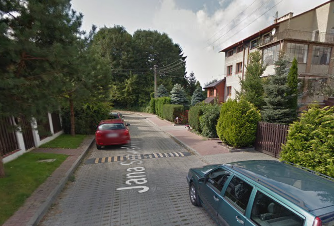 Współczesne zdjęcie. Przedstawia widok na ulicę w mieście, wewnątrz osiedla domków jednorodzinnych. Jest to Ulica Jana Sobieskiego w Lublinie. 