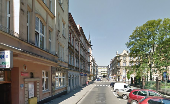 Współczesne zdjęcie. Przedstawia stare, zabytkowe kamienice i ulicę. Jest to ulica Jana III Sobieskiego w Chorzowie. 