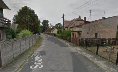 Współczesne zdjęcie. Przedstawia widok ulicy w mieście. Z prawej i lewej strony stare zabudowania. Jest to Ulica Sobieskiego w Olsztynie. 