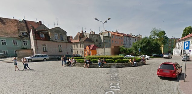 Współczesne zdjęcie. Widok na mały plac w miasteczku. Naokoło kamienice. Jest to Plac Jana III Sobieskiego w Wołowie.