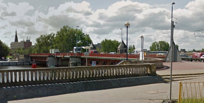 Współczesne zdjęcie. Widok na most w mieście. Gdzieniegdzie widać budynki. Jest to Most Długi im. Jana III Sobieskiego w Szczecinie.