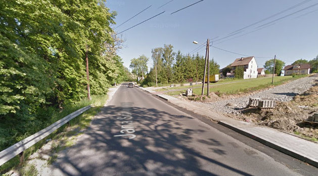 Współczesne zdjęcie. Przedstawia widok na ulicę w małym mieście. Po prawej stronie plac budowy i dom, po lewej drzewa. Jest to Ulica Jana Sobieskiego w Myślenicach. 