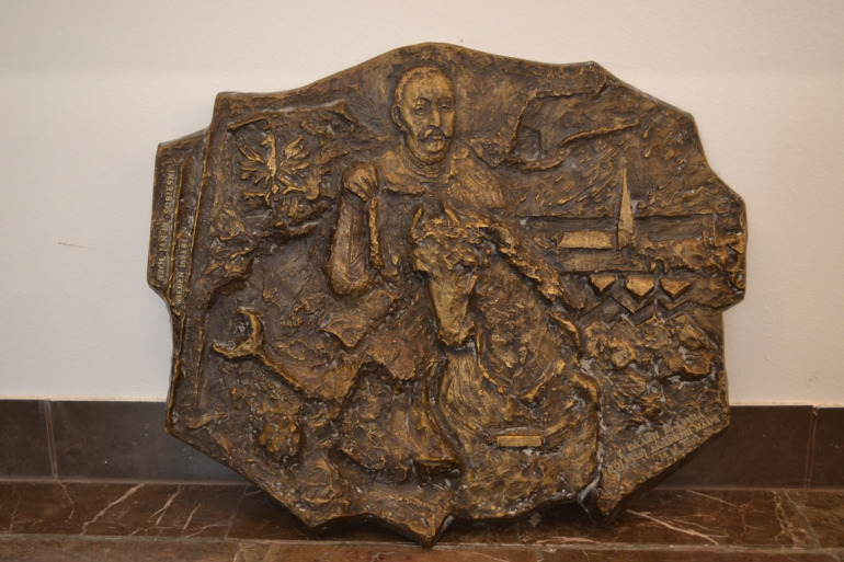 Zdjęcie przedstawia płaskorzeźbę, która znajduje się w sali konferencyjnej w Stacji Naukowej Polskiej Akademii Nauk. Jest to przedstawienie Jana III Sobieskiego na koniu. Po lewej stronie orzeł  w koronie. 