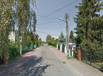 Współczesne zdjęcie. Przedstawia asfaltową drogę, przy której rosną drzewa. Jest to Ulica Królewicza Jakuba w Warszawie. 