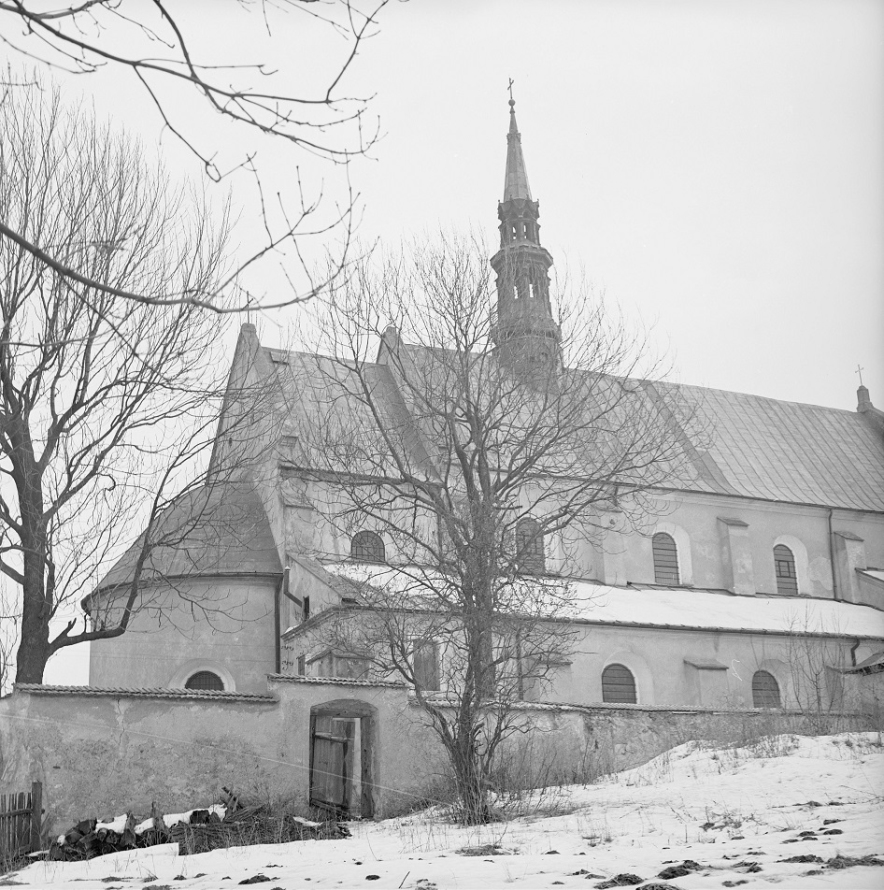 Czarno-białe zdjęcie. Przedstawia pejzaż zimowy i kościół. Jest to Raków, 17-wieczny kościół św. Trójcy wzniesiony na gruzach zboru ariańskiego. 